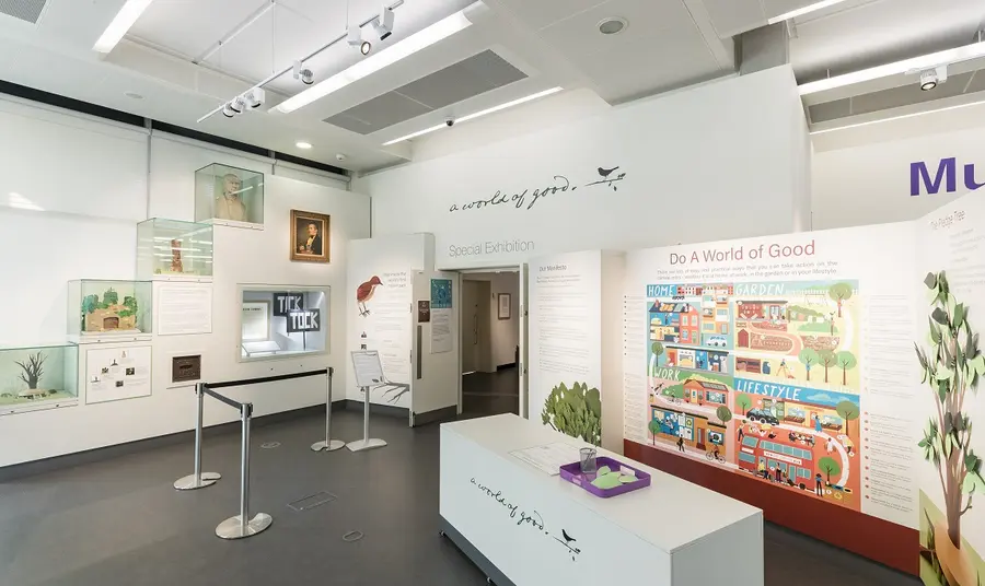 A brightly lit room with an exhibition including paper sculptures of birds and information panels