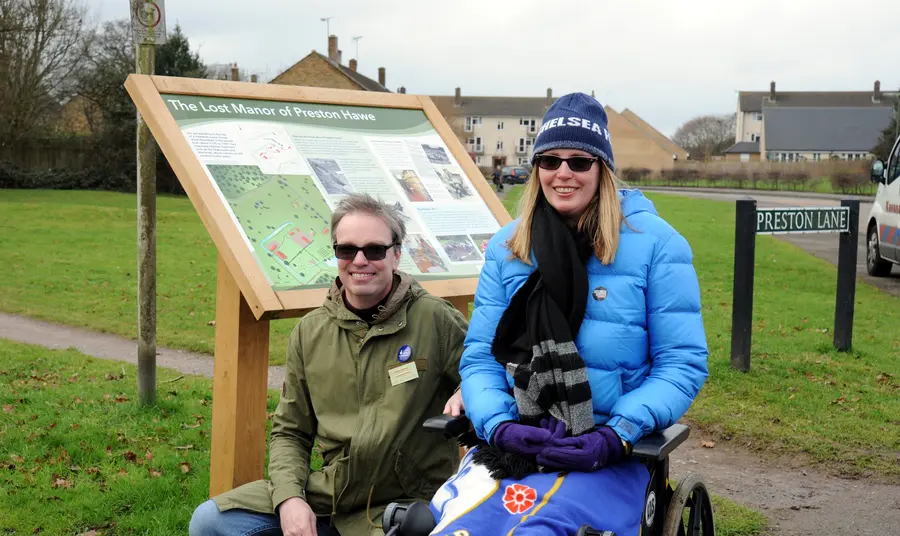 Volunteers Wayne and Antoinette by an information board