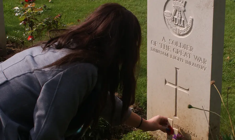 A student from King James I Academy lays a poppy on the grave of an unknown Durham solider