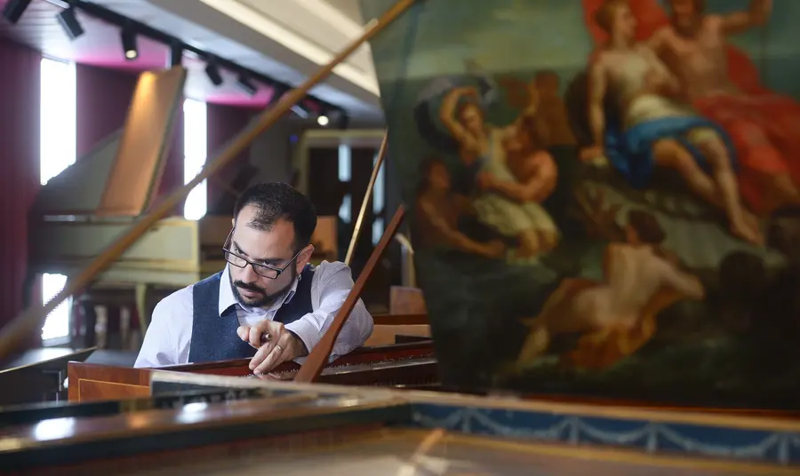 Conservator Jonathan Santa Maria Bouquet tuning a harpsichord in the museum 