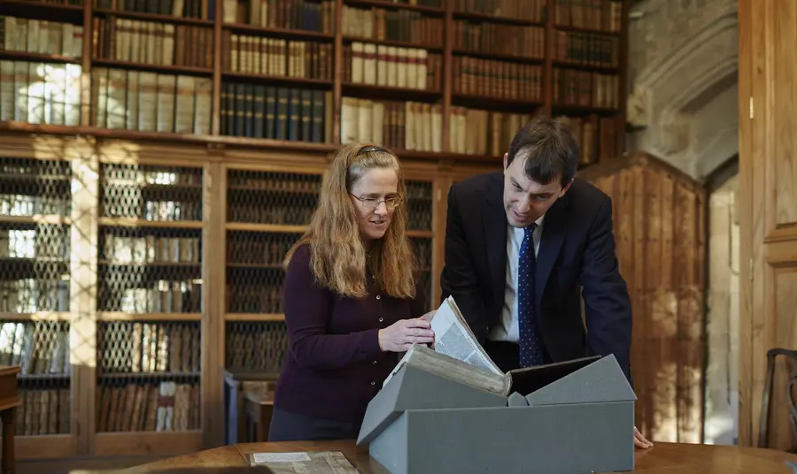 Cathedral Archivist Emily Naish and John Glen MP examine a book from the collection