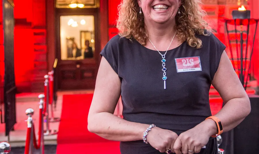 Karen Perkins stands at a red carpet event, smiling broadly