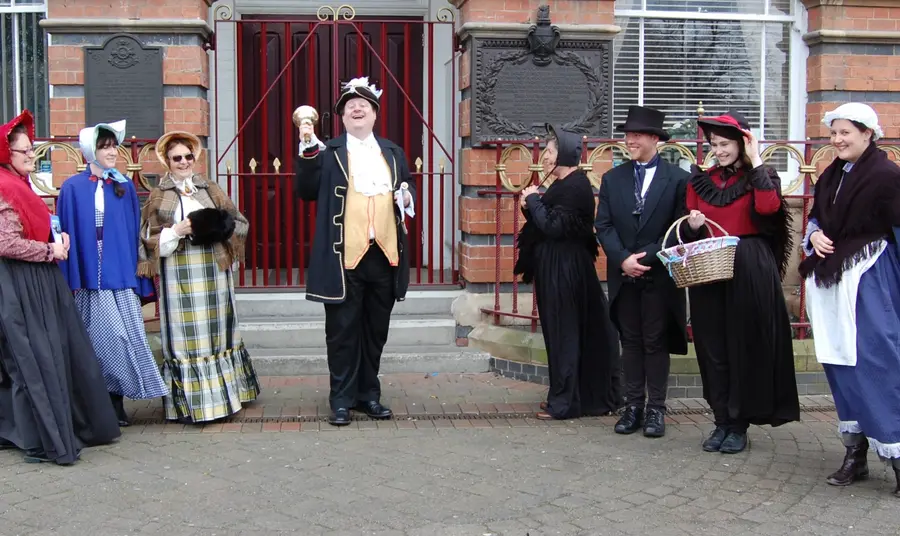 A bell ringer and other people in historic dress