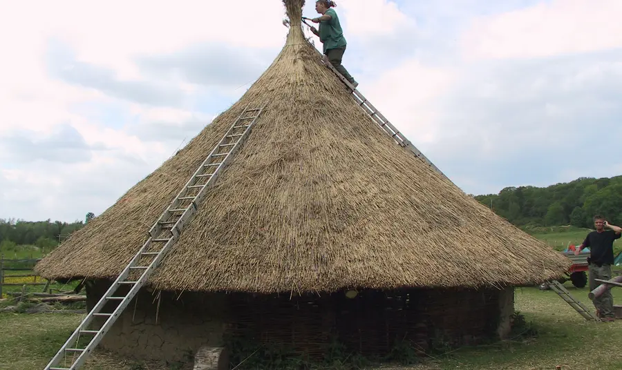 A trainee rethatches a roundhouse