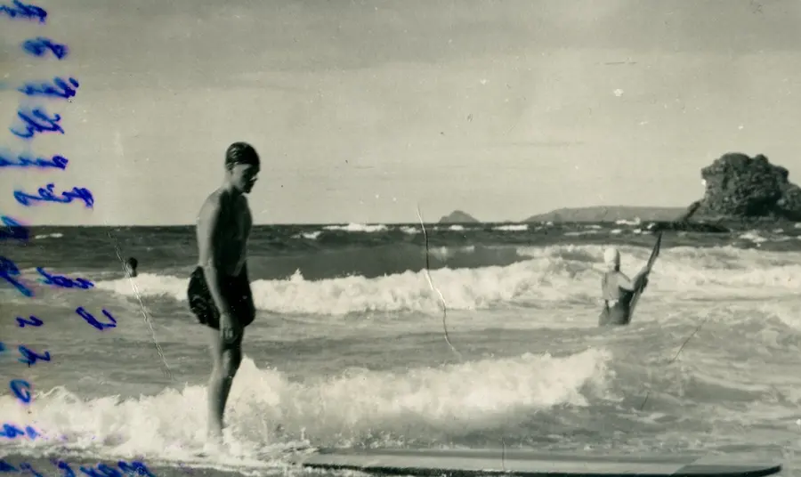 A black and white photograph of a surfer on a long board