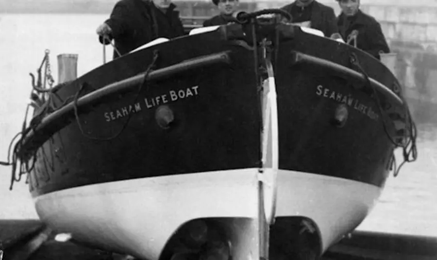 Five men stand in a life boat ready to be launched