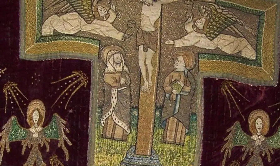 An image of a medival vestment showing a crucifix, religious figures and angles.