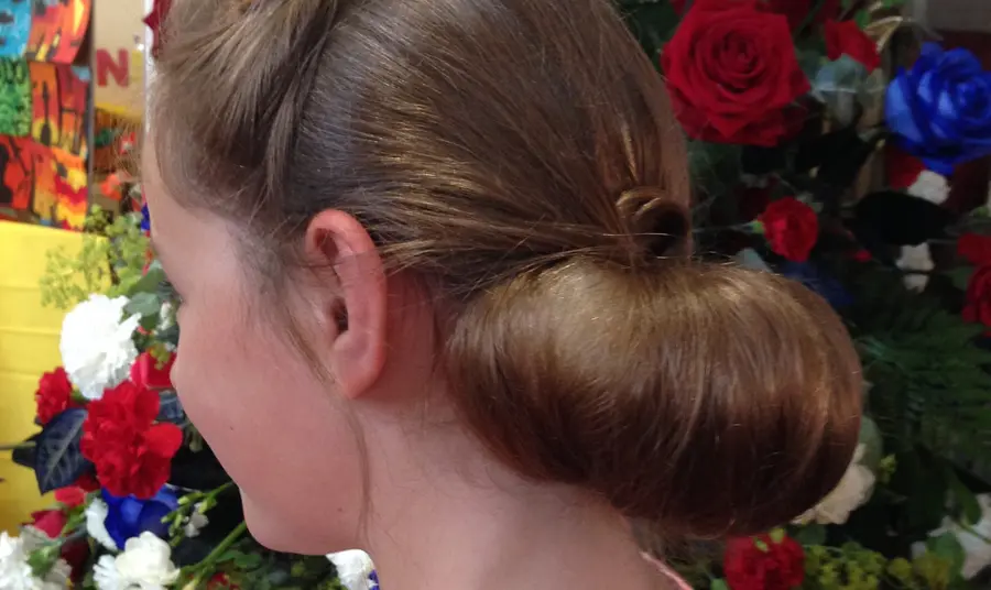 A young lady with a 1940s style chiffon beside a church flower display