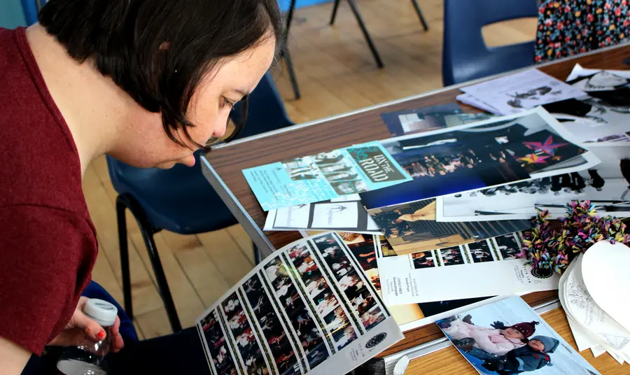 A person at a table looking at photographs and other archive material