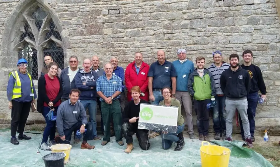 A group of people with gloves and buckets standing in front of a church wall