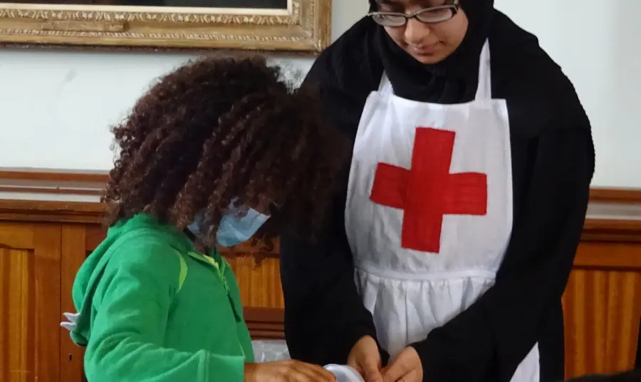 A young participant demonstrates wartime medical techniques to a young visitor