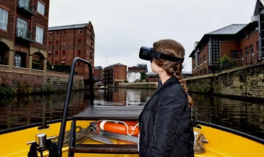 A young women wearing head gear examining the urban landscape from a boat on a canal