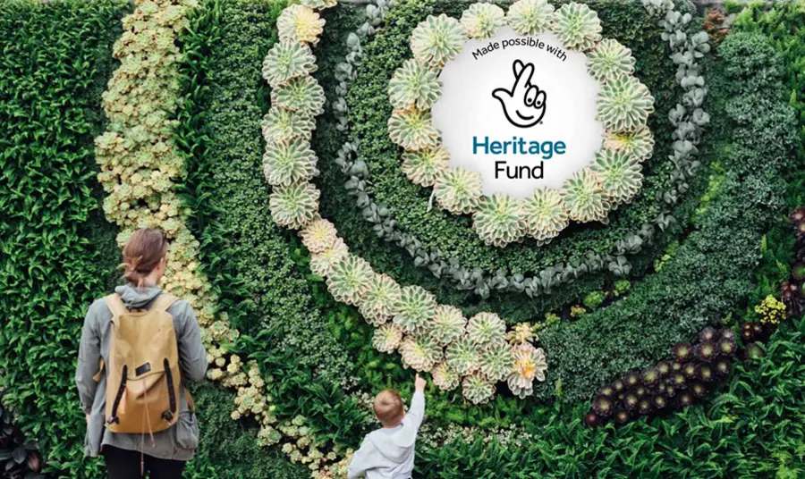 A young child pointing at a plaque of our acknowledgement stamp that is placed in the middle of a garden wall