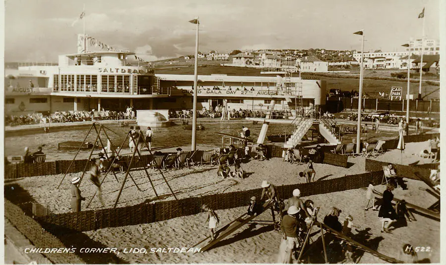 A black and white photograph of a busy children's play area in front of a lido.