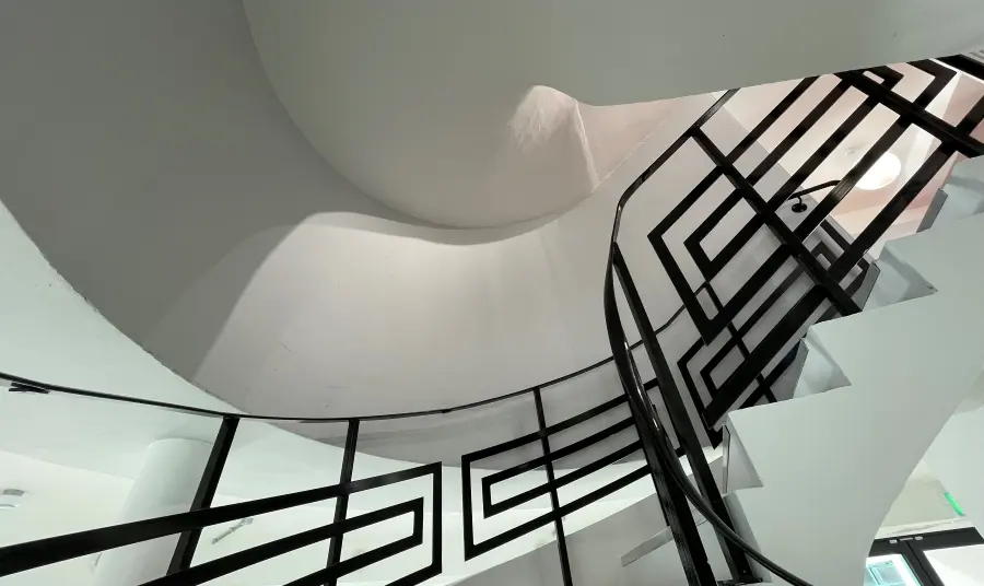 Looking up at the Art Deco rotunda staircase with white stairs and black metal hand rails
