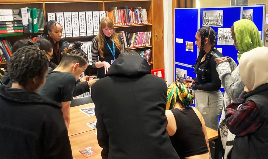 A group of people working around a table looking at research materials