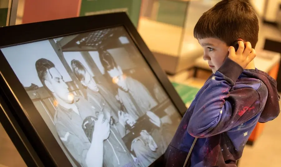 A child looking at an old image on a digital screen in The Story exhibition 
