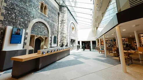 A large atrium with a castle's stone wall on the left and shop and restaurant on the right
