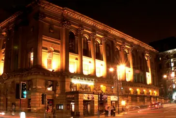 St George's Hall at night, lit up in the spaces between the columns 