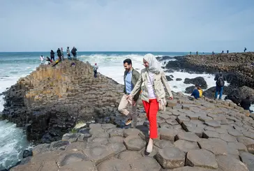 People walk across the iconic landscape of the Giant's Causeway coastal route