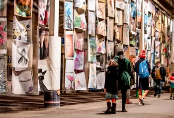 Artwork created by local people on display with a group of people studying them. 