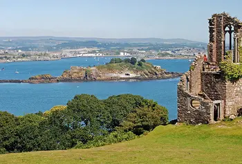 A ruined folly with a coastal landscape during summer in the background