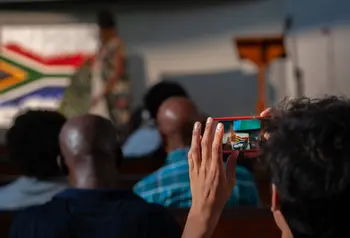 Person taking a picture of the South African flag on a phone camera at The Anti-Apartheid Legacy: Centre of Memory and Learning event