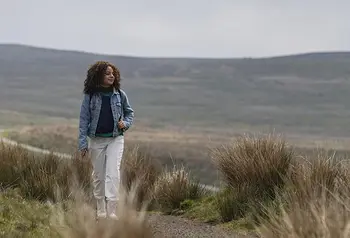 A young woman walks through a moorland landscape