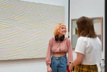 Two Gallery visitors in front of a Bridget Riley patterned painting