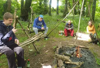 People chat round a campfire in woodland