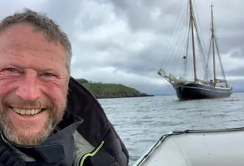 Person smiling at camera with boat in the background