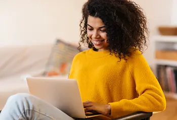 Young woman smiling as she looks at a laptop screen