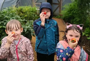 Tri phlentyn yn dal tomatos i'w trwynau