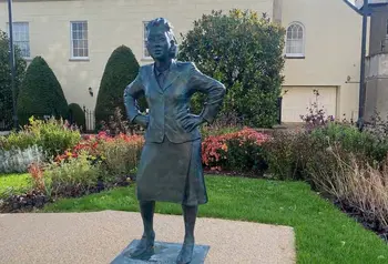 Life-sized statue of a woman in a small, landscaped garden