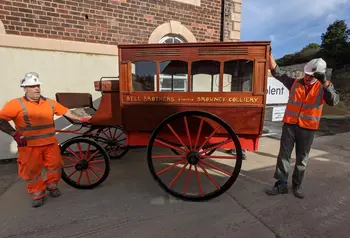 Two workmen standing either side of the horse-drawn ambulance