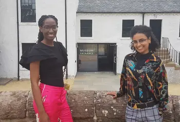 Two people smiling and standing in front of a museum entrance