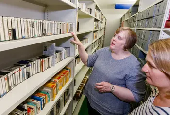 Two people looking at tapes on shelves