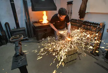 A blacksmith hitting metal, surrounded by a spray of sparks