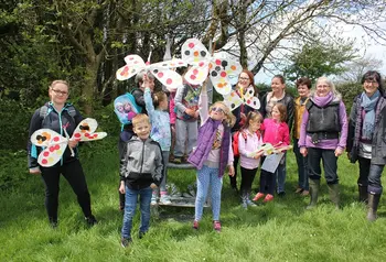 Group of volunteers and children in a park waving paper butterflies