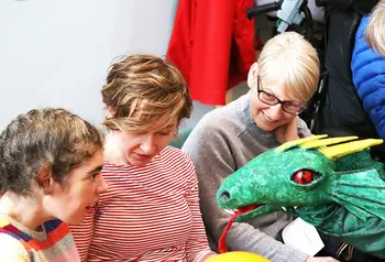 Young girl interacting with a dragon puppet during a PAMIS story telling session