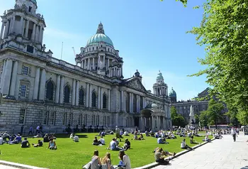 People sitting on grass in front of large building