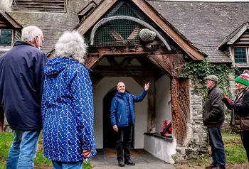 An outdoor scene of a person welcoming a group of people to a church