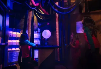 Three children interact with the hovering ball exhibit and balance balls on different air streams