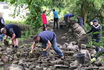 Volunteers work on rebuilding dry stone walls at St Nicholas Church, 