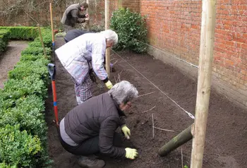 Four people tending to garden bed