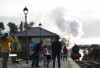 Family gathered on the platform at Whitehead Railway station watching a locomotive approach