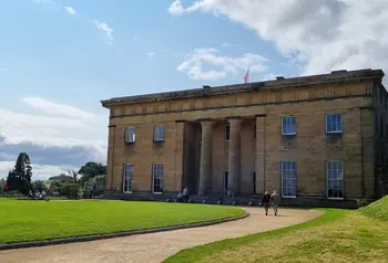 The facade of Belsay Hall on a sunny day, with visitors exploring the grounds