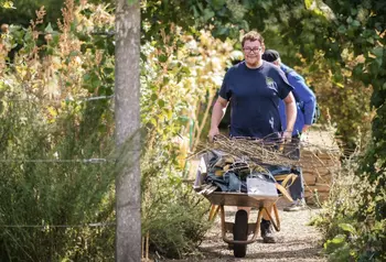 A volunteer with a wheelbarrow of debris, cleaning up the Chelsea Physic Gardens