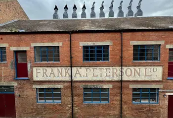 A front of a red brick building with many chimneys on top of the fish smokehouse 