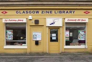 A yellow building on a city street with a writing saying Glasgow Zine Library